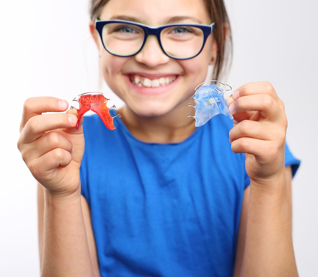 Smiling girl holding retainers